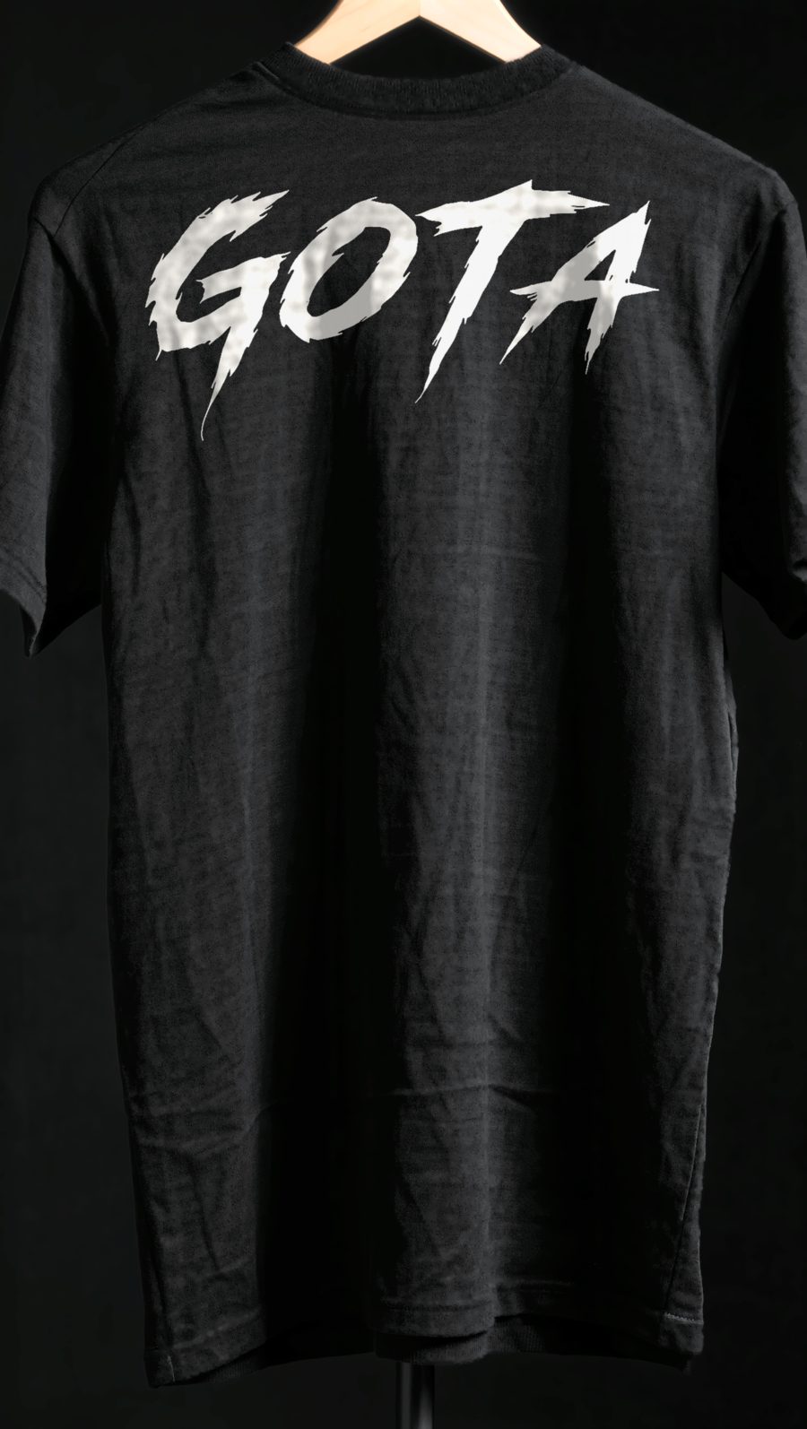 Black GOTA tee hanging, back with the large lettering