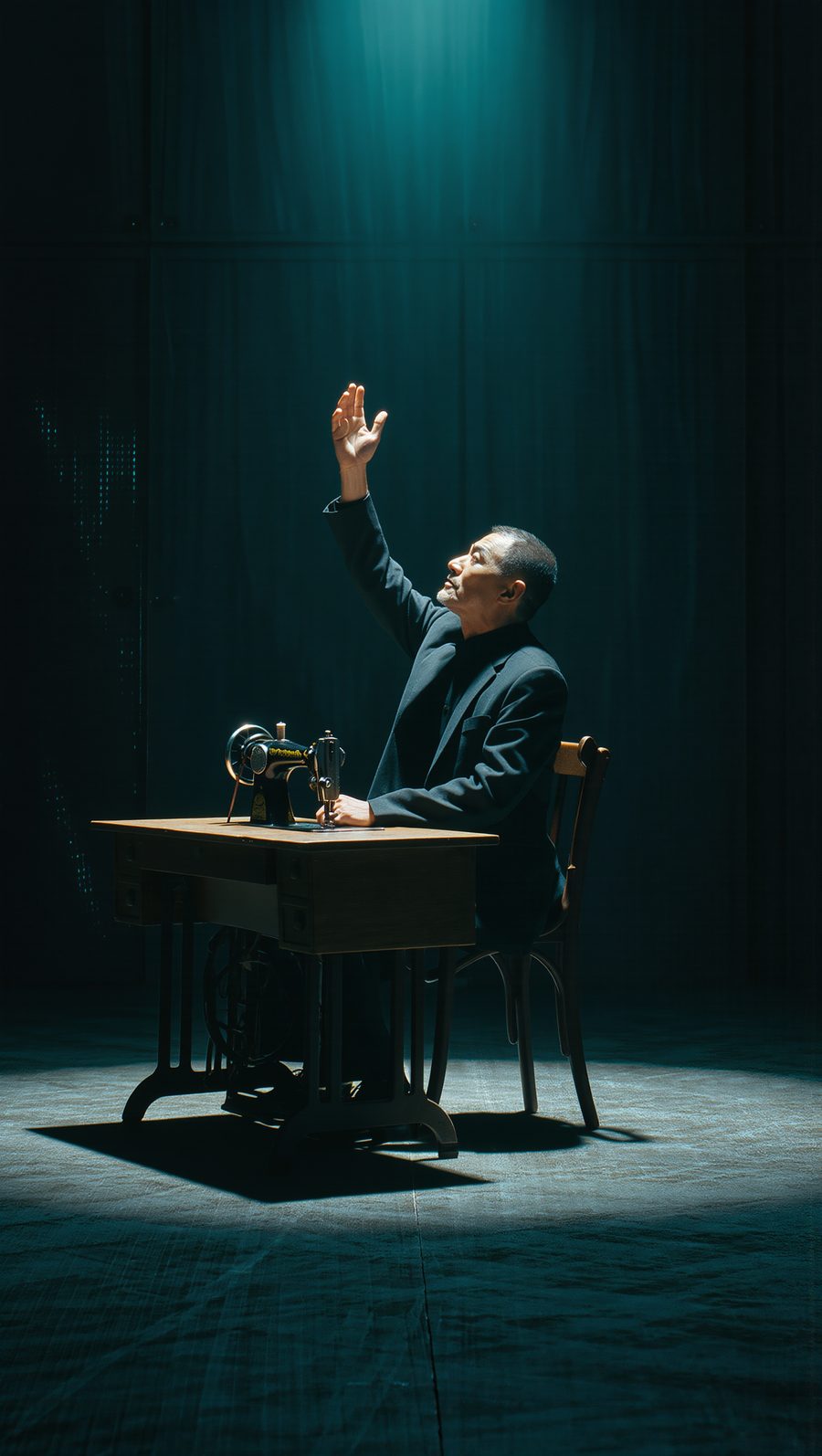 A man at an old sewing machine under a single light